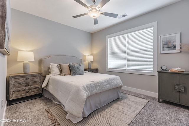 bedroom with visible vents, baseboards, light colored carpet, and ceiling fan