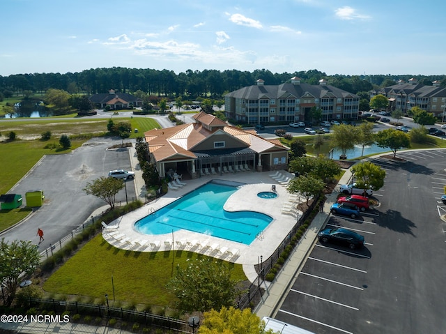 community pool with a patio area, a fenced backyard, and a water view
