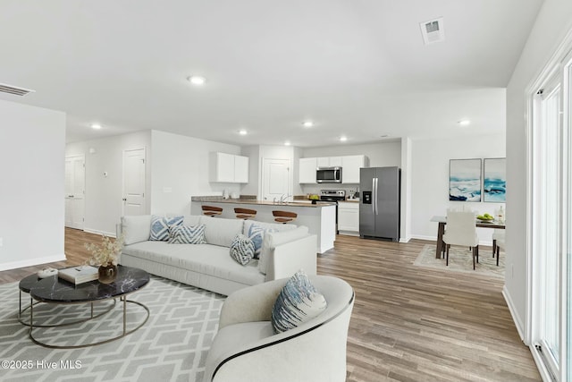 living area featuring recessed lighting, visible vents, and light wood finished floors