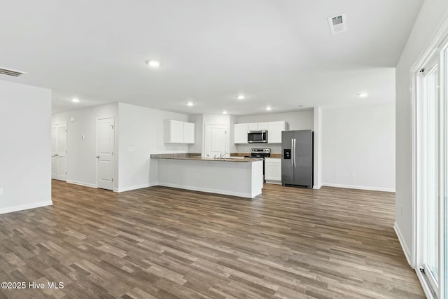 kitchen featuring baseboards, dark wood-type flooring, appliances with stainless steel finishes, and open floor plan