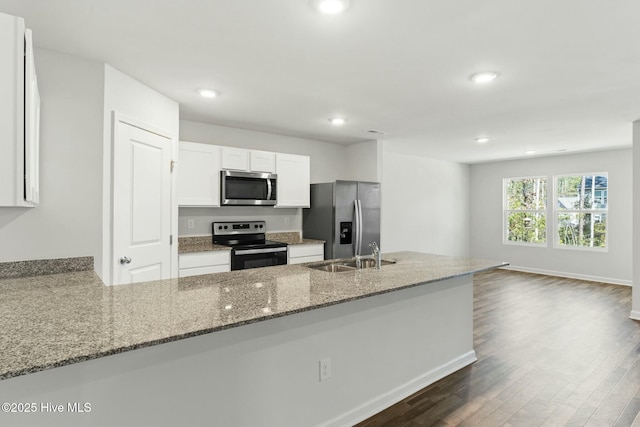 kitchen featuring a sink, stone counters, appliances with stainless steel finishes, white cabinetry, and dark wood-style flooring