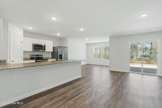 kitchen featuring recessed lighting, stainless steel appliances, white cabinets, light stone countertops, and dark wood-style flooring