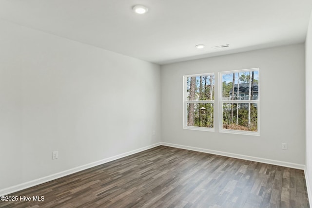 spare room with visible vents, baseboards, and dark wood finished floors