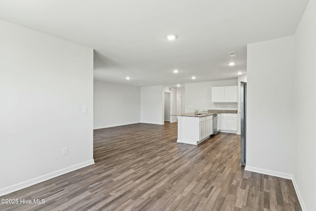 unfurnished living room with dark wood-type flooring, recessed lighting, baseboards, and a sink