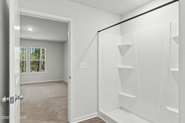 bathroom with a shower and baseboards