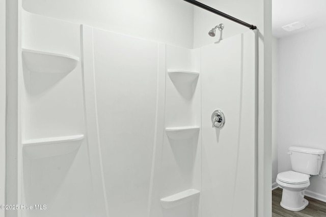 full bathroom with toilet, wood finished floors, a stall shower, and baseboards