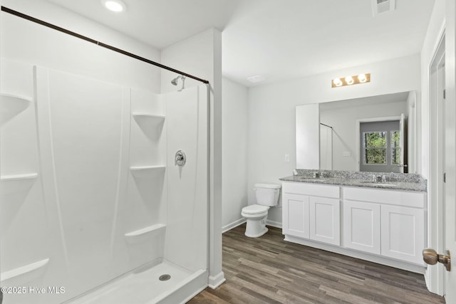 full bath with wood finished floors, double vanity, a stall shower, a sink, and toilet