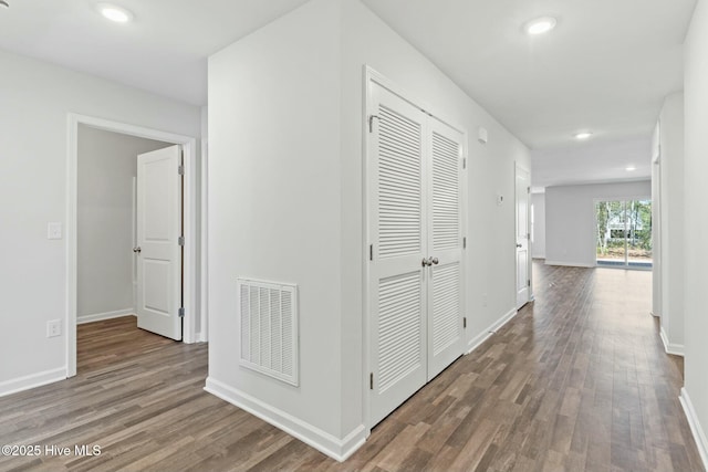 hallway with visible vents, recessed lighting, baseboards, and wood finished floors