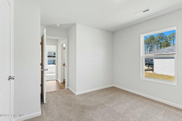 spare room featuring visible vents, carpet flooring, and baseboards