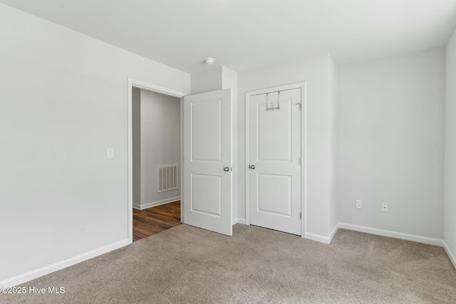 unfurnished bedroom featuring a closet, visible vents, carpet flooring, and baseboards