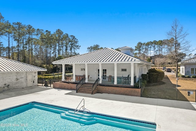 rear view of house featuring a fenced in pool, fence, a porch, a patio area, and a standing seam roof