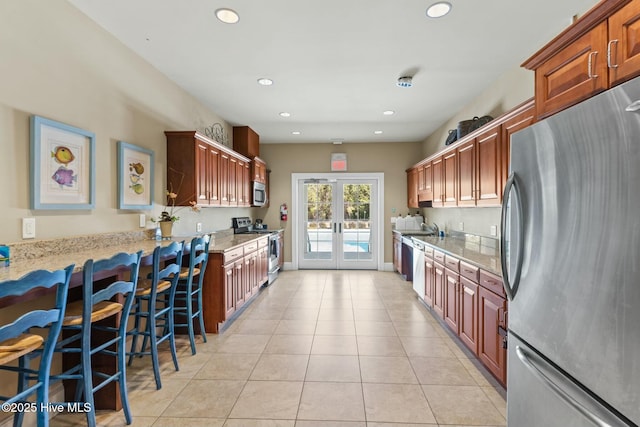 kitchen with light stone countertops, light tile patterned floors, recessed lighting, french doors, and stainless steel appliances