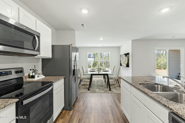 kitchen with dark wood finished floors, recessed lighting, appliances with stainless steel finishes, white cabinets, and a sink