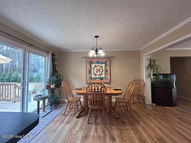 dining area with crown molding, baseboards, light wood-style floors, a notable chandelier, and a textured ceiling