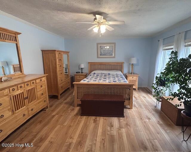 bedroom featuring ornamental molding, a textured ceiling, light wood-style floors, and a ceiling fan