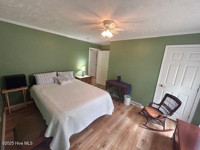 bedroom with crown molding, wood finished floors, baseboards, and a textured ceiling