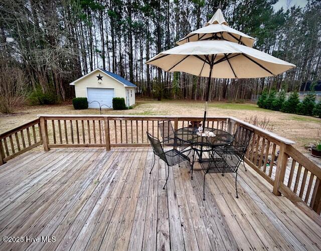 wooden deck with a garage, an outdoor structure, and outdoor dining space