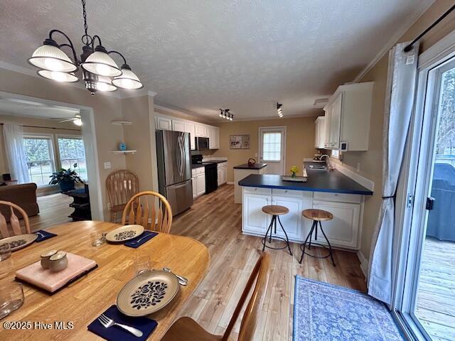 dining space featuring light wood-style flooring, a wealth of natural light, and a textured ceiling