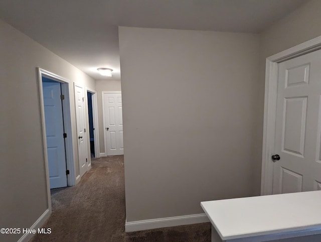 corridor with dark colored carpet and baseboards