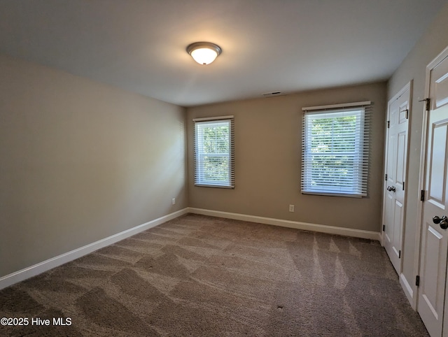 unfurnished room with carpet flooring, baseboards, and plenty of natural light