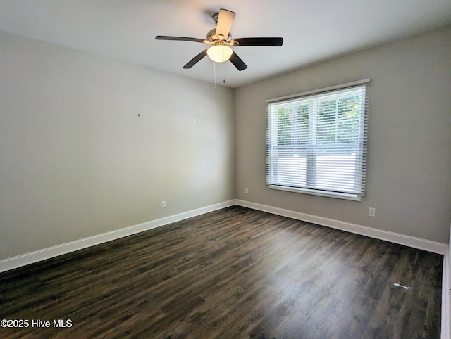 empty room with dark wood-style floors, baseboards, and ceiling fan