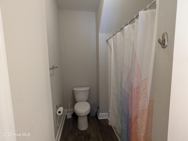 bathroom featuring toilet, a shower with shower curtain, baseboards, and wood finished floors