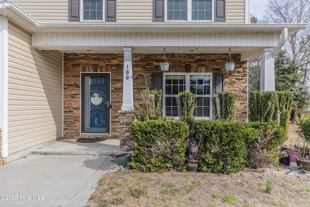 view of exterior entry with stone siding and covered porch