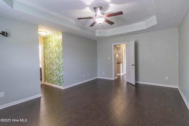 unfurnished room featuring a raised ceiling, a ceiling fan, crown molding, baseboards, and dark wood-style flooring