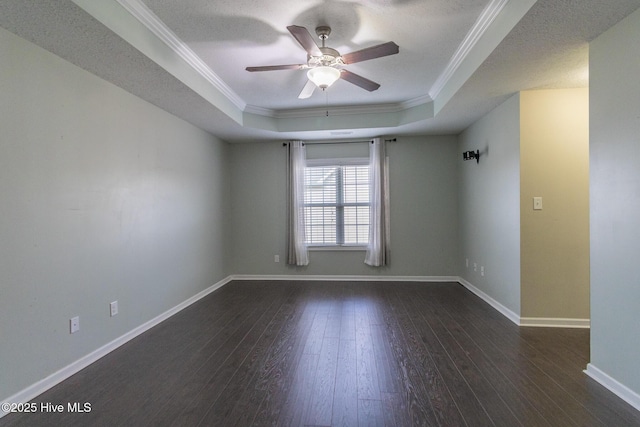 empty room with a raised ceiling, hardwood / wood-style floors, crown molding, baseboards, and ceiling fan