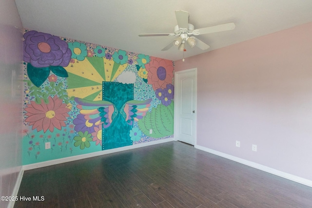 unfurnished room featuring an accent wall, wood finished floors, baseboards, and ceiling fan