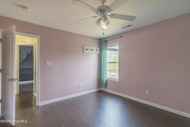 empty room with dark wood-style floors, a ceiling fan, visible vents, and baseboards