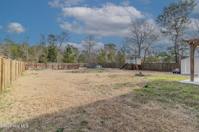 view of yard featuring an outdoor structure, a playground, a storage unit, and a fenced backyard