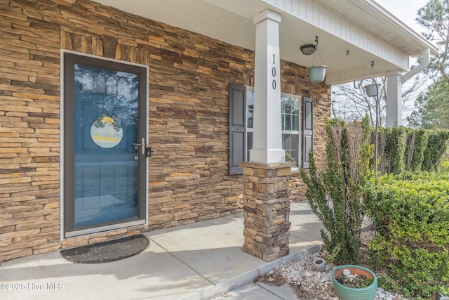 property entrance with covered porch and stone siding