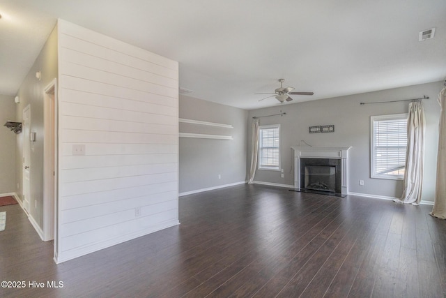 unfurnished living room featuring a wealth of natural light, visible vents, dark wood-type flooring, and ceiling fan