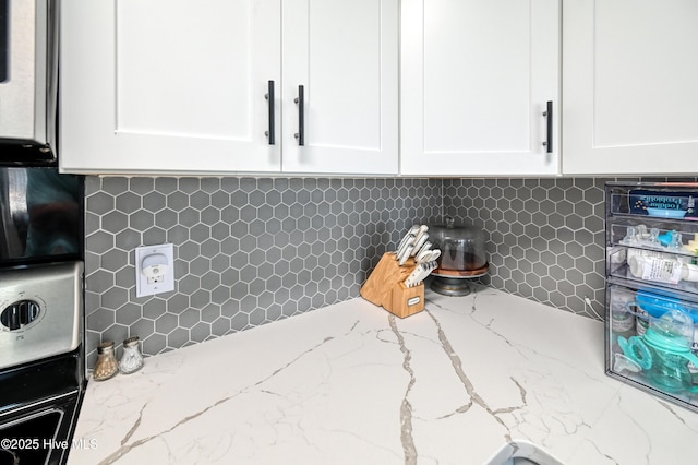 details with tasteful backsplash, white cabinets, and light stone counters