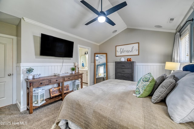 carpeted bedroom featuring visible vents, ornamental molding, a ceiling fan, wainscoting, and vaulted ceiling