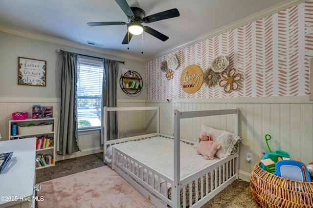 carpeted bedroom featuring a wainscoted wall, visible vents, and crown molding