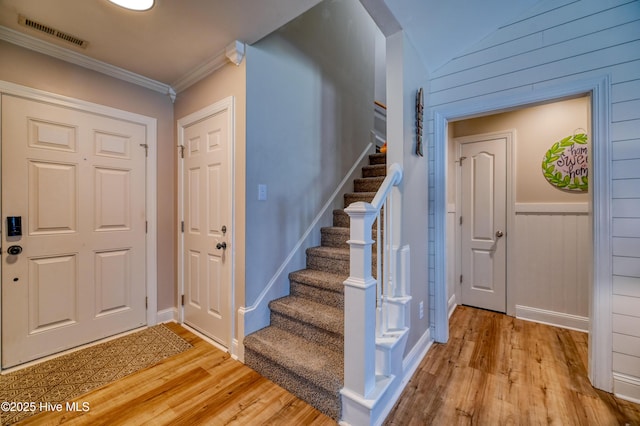 foyer entrance featuring light wood-type flooring, visible vents, stairs, and crown molding