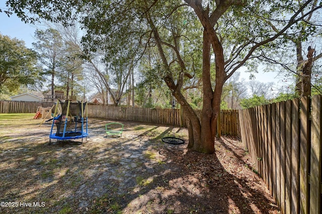 view of yard featuring a playground, a trampoline, and a fenced backyard