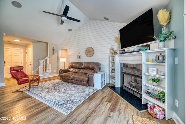 living area with stairs, lofted ceiling, wood finished floors, and a fireplace