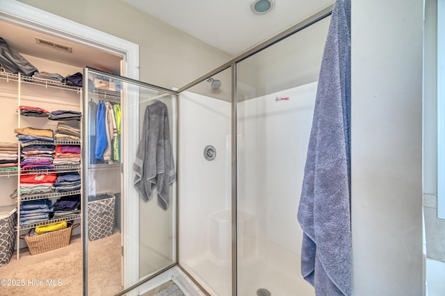 full bath featuring visible vents, a shower stall, and a walk in closet