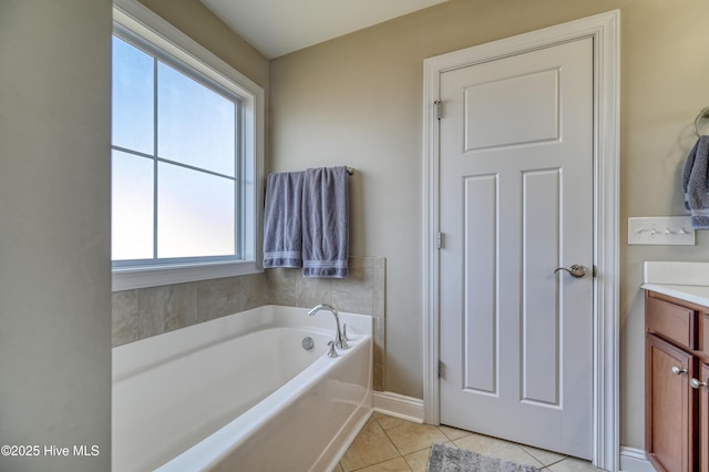 bathroom featuring tile patterned flooring, a bath, vanity, and baseboards