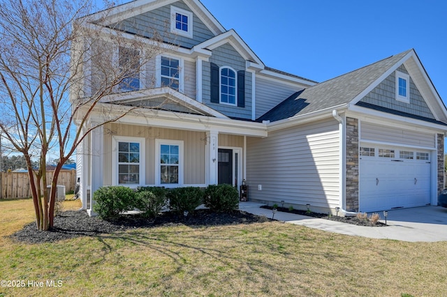 view of front facade with stone siding, concrete driveway, a front lawn, and fence