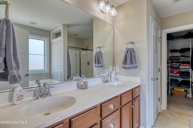 bathroom with tile patterned flooring, a shower stall, double vanity, and a sink