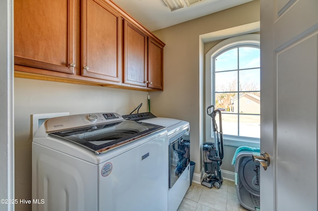 laundry room with light tile patterned flooring, washing machine and dryer, cabinet space, and baseboards