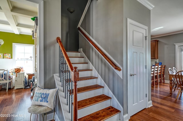 stairway featuring beamed ceiling, coffered ceiling, wood finished floors, and ornamental molding