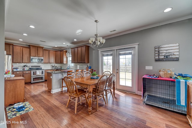 dining area featuring visible vents, light wood-type flooring, ornamental molding, recessed lighting, and a notable chandelier