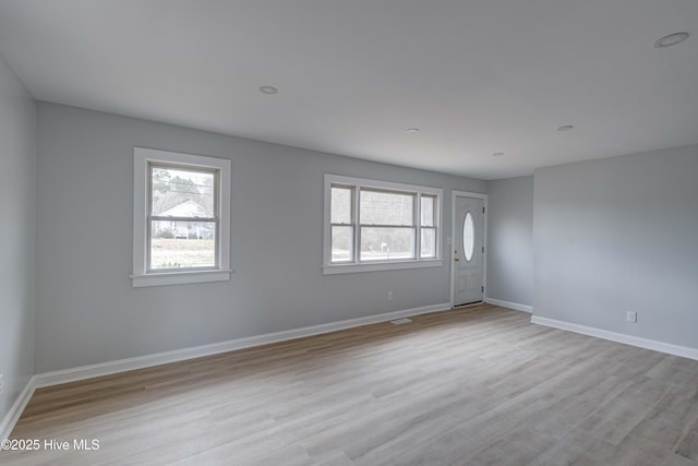 spare room featuring baseboards and light wood-style floors