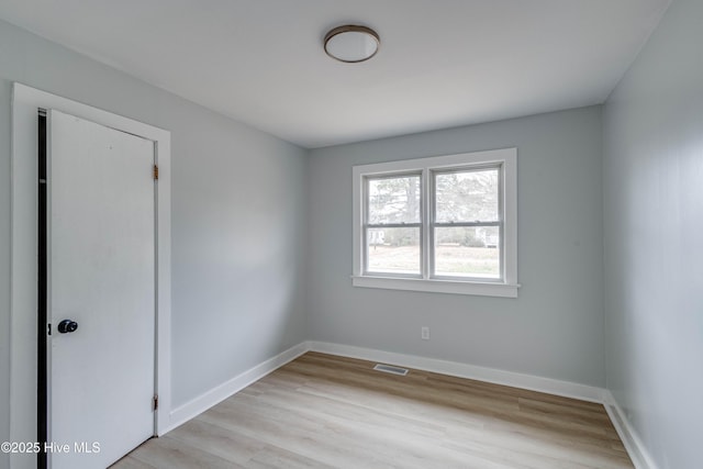 empty room with baseboards, visible vents, and light wood-type flooring