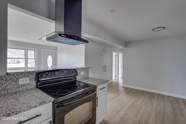 kitchen with electric range, light wood-style floors, white cabinets, light stone countertops, and extractor fan